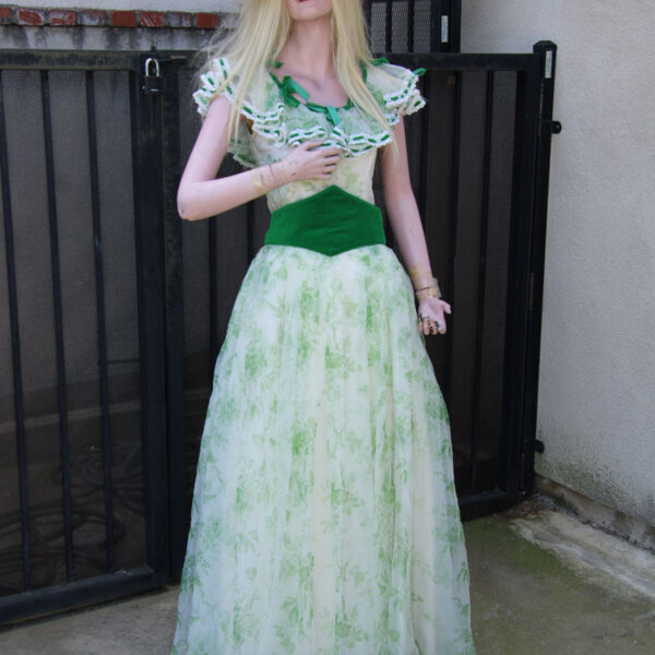 Lady mannequin dress in a vintage green dress with hat.
