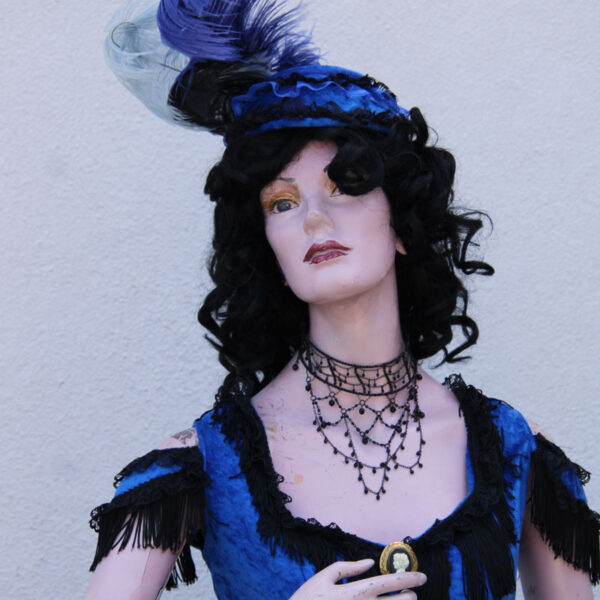 Lady mannequin dress in a vintage blue and black dress with hat, close up.