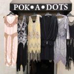 Assorted vintage women dresses hanging on the outside awning of Pok-A-Dots Costumes.