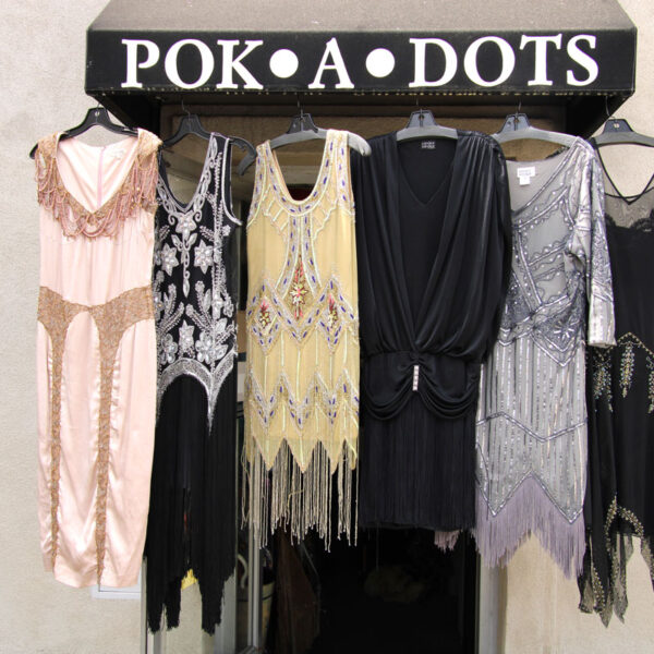 Assorted vintage women dresses hanging on the outside awning of Pok-A-Dots Costumes.