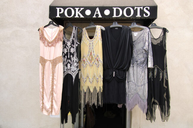 Assorted vintage women dresses hanging on the outside awning of Pok-A-Dots Costumes.