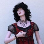 Lady mannequin in a red vintage dress and black wig, close up shot.