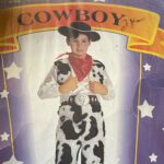 Young boy in a cowboy costume on the cover of a plastic package.