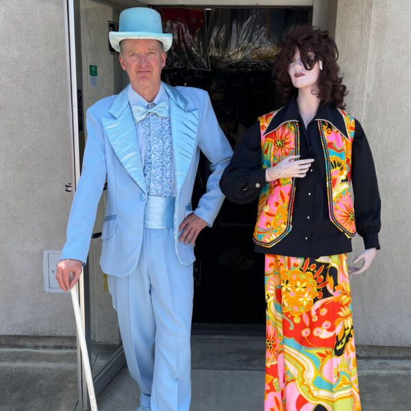 Man dressed in 20's blue suit with top hat and a lady mannequin in orange colored dress.