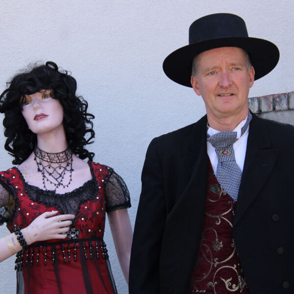 Man dressed in cowboy suite and lady mannequin in a red dress.