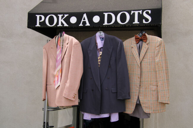 Men suits hanging from the sign of Pok-a-Dots awning.