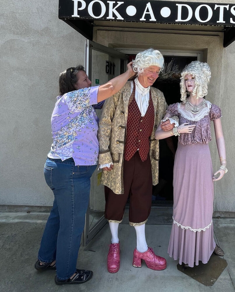 Cari Nuss dressing up a man in a costume.