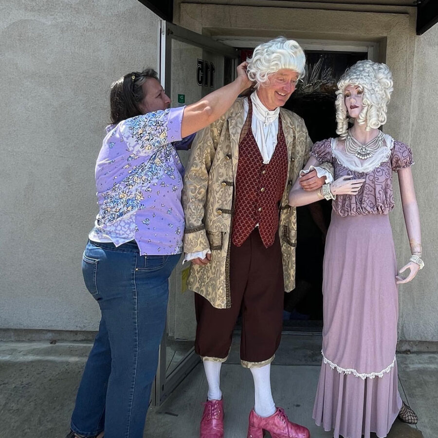 Cari Nuss dressing up a man in a costume.